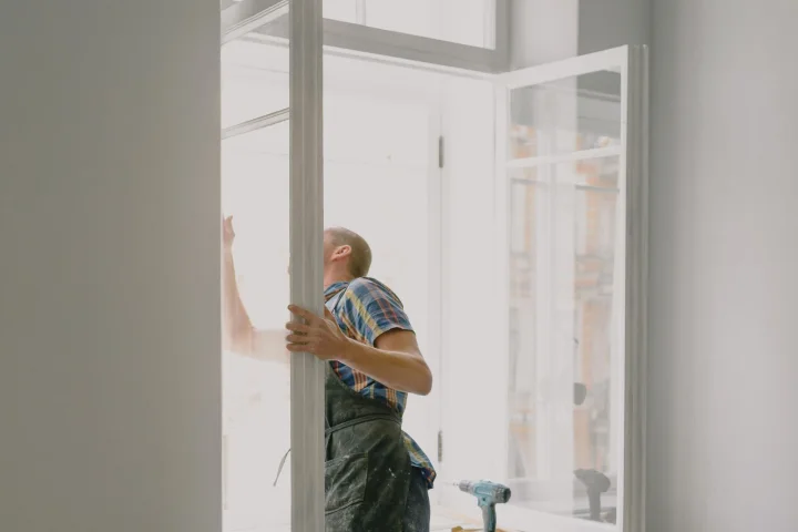 Artisan posant une fenêtre dans un logement en rénovation